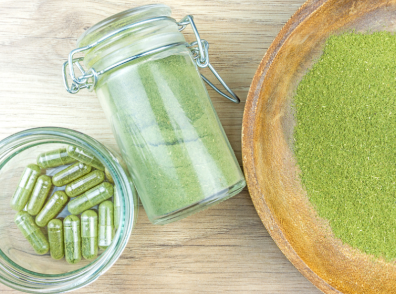 Green powder alongside capsules filled with green powder